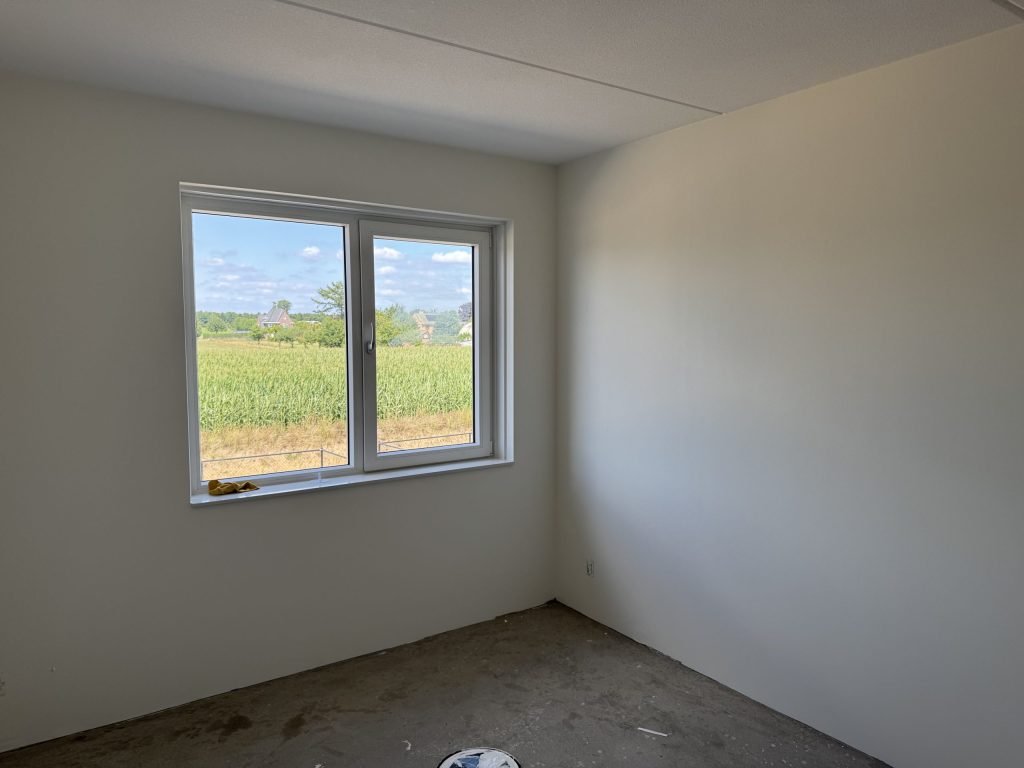 Lege nieuwbouwkamer met gladde lichte wanden en een groot raam